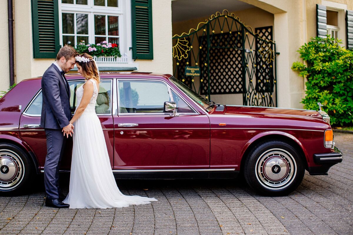 Roter Oldtimer Rolls Royce des Hotels mit Brautpaar davor