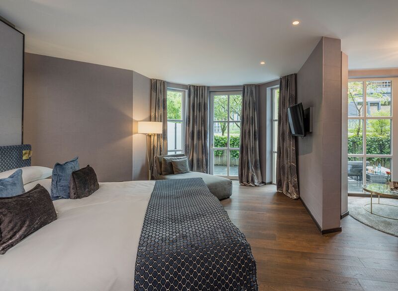 Spacious Residence Junior Suite with a double bed, seating area and garden views at Parkhotel Adler.
