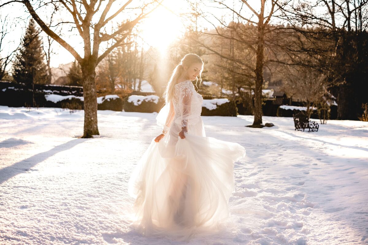 Hochzeit im Winter - Braut steht mit wundervollem Kleid im Sonnenschein
