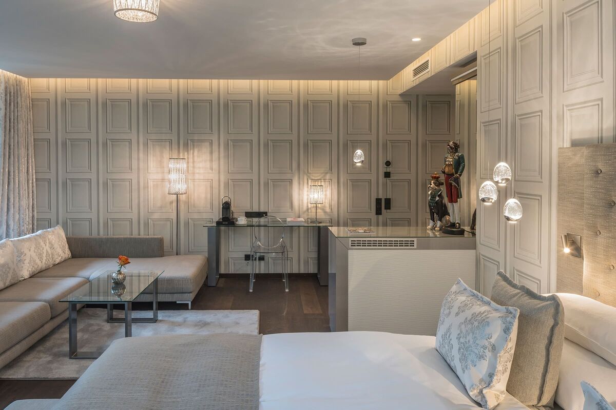 Stylish combined living and sleeping area of the Adler Suite with a double bed, sofa and desk.